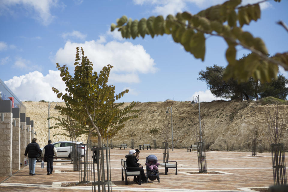 In this photo taken Wednesday, Feb. 15, 2017, a couple sit on a bench in Har Homa neighborhood in east Jerusalem. For many Israelis, Har Homa has become another neighborhood in Jerusalem, served by city bus lines, schools and public services. Its quiet streets are lined with apartment buildings, pizza shops, supermarkets and pharmacies. But for the Palestinians, this unassuming neighborhood is far more. It is an illegal settlement in east Jerusalem, and in some ways, the most damaging. (AP Photo/Dan Balilty)