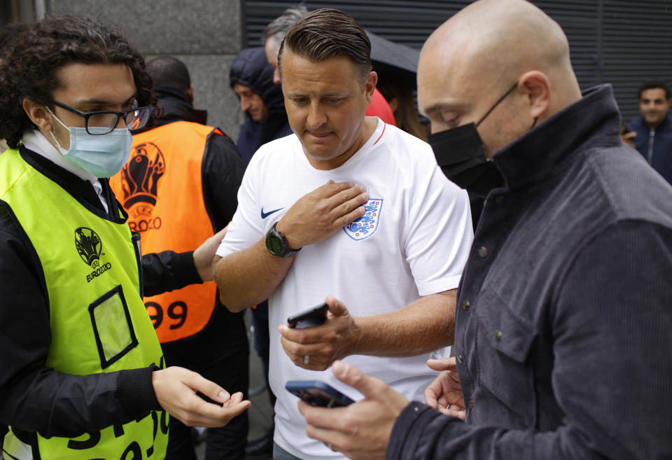 Empleados del estadio Wembley revisan los boletos electrónicos de los aficionados previo a la final de la Euro 2020 entre Inglaterra e Italia, el domingo 11 de julio de 2021, en Londres. (AP Foto/David Cliff)