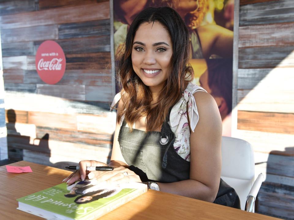 Ayesha Curry smiles as she signs a book at an event in 2017.