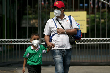 A student and his father wear masks outside a public school, as classes in over 400 Bangkok schools have been cancelled due to worsening air pollution, in Bangkok, Thailand, January 30, 2019. REUTERS/Athit Perawongmetha