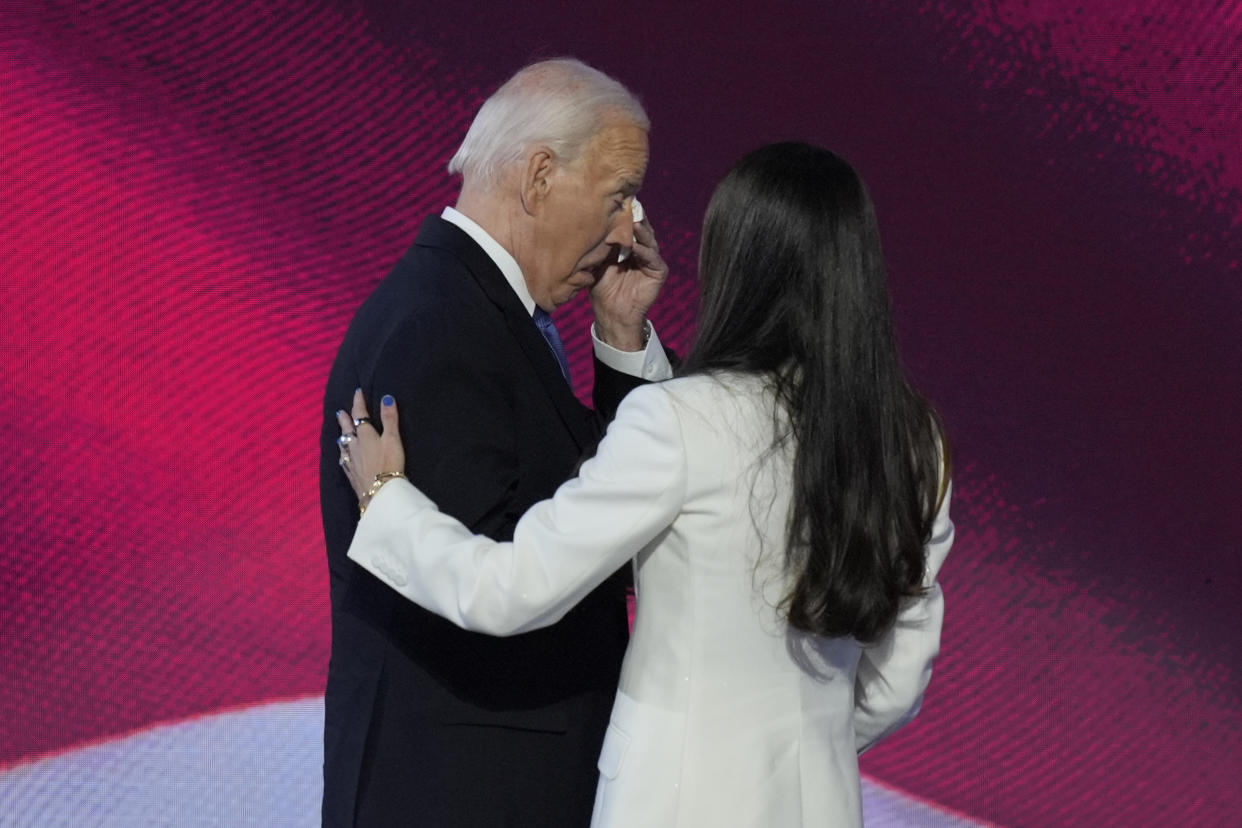 President Biden appears to wipe his eyes while Ashley Biden holds her hand against his back.