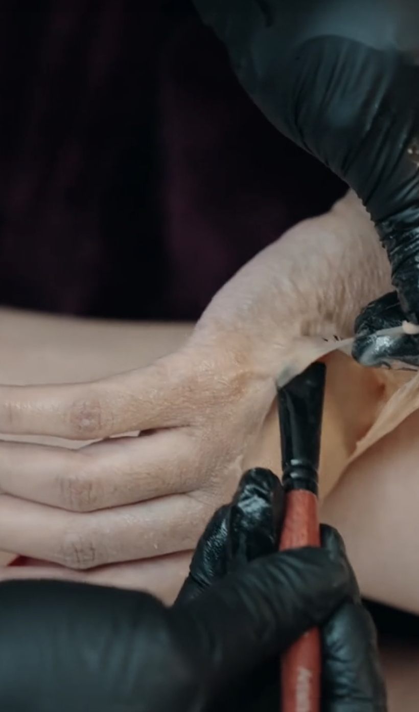 Someone applying prosthetics to Cardi's hand