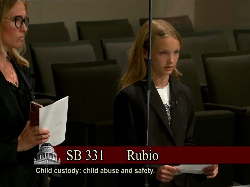 A young girl speaks before the California State Senate with her mother at her side.