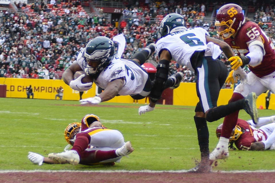 Philadelphia Eagles running back Boston Scott (35) leaps over Washington Football Team cornerback Kendall Fuller (29) to score a touchdown during the second half of an NFL football game, Sunday, Jan. 2, 2022, in Landover, Md. (AP Photo/Mark Tenally)