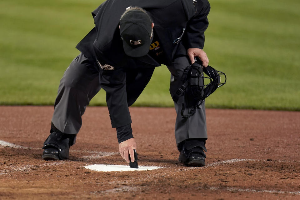 Umpire Joe West brushes off home plate between batters during the third inning of a baseball game between the St. Louis Cardinals and the Cincinnati Reds Friday, April 23, 2021, in St. Louis. (AP Photo/Jeff Roberson)