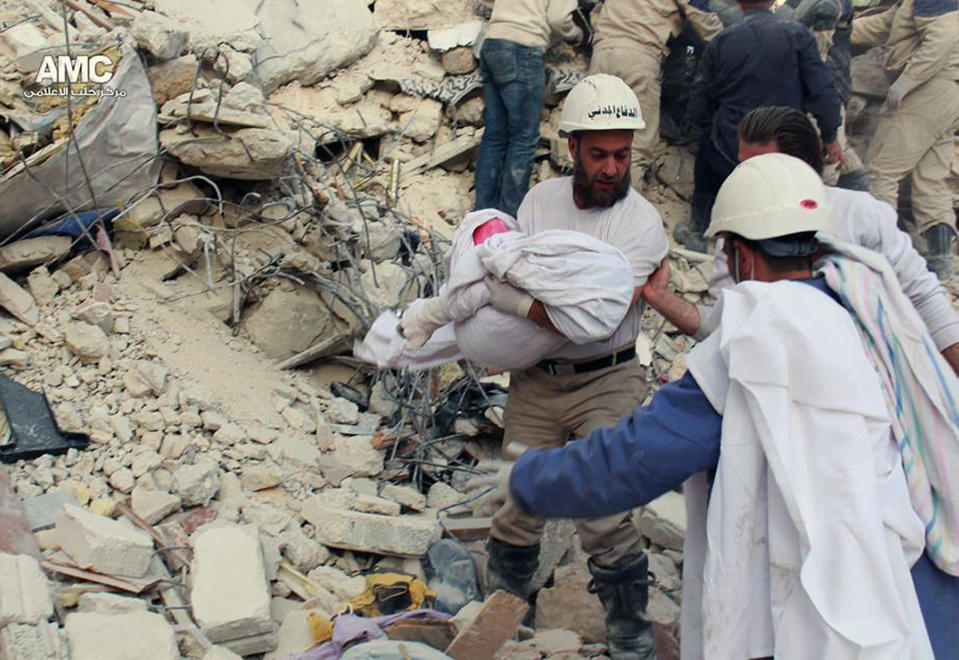 A Sunday, April 6, 2014 photo provided by the anti-government activist group Aleppo Media Center (AMC), which has been authenticated based on its contents and other AP reporting, shows civil defense rescue workers carrying the body of a victim of a Syrian government airstrike, in Aleppo, Syria. (AP Photo/Aleppo Media Center, AMC)