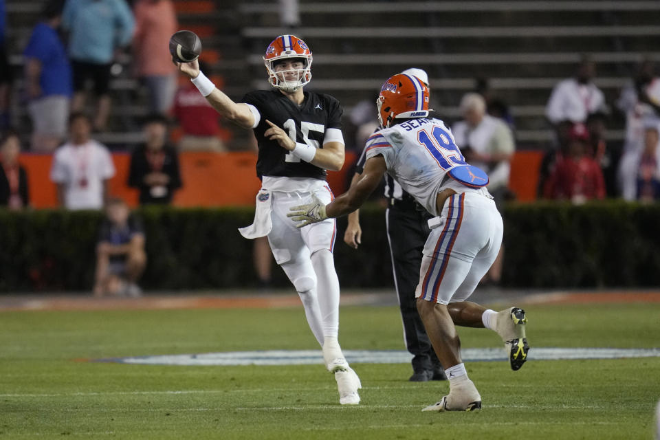 Florida quarterback Graham Mertz, left, throws a pass as he is pressured by edge T.J. Searcy (19) during the second half of the NCAA college football team's annual Orange and Blue spring game Thursday, April 13, 2023, in Gainesville, Fla. (AP Photo/John Raoux)