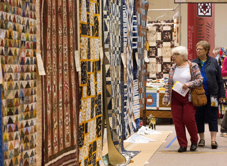 FILE - Two women look over quilts on display, Saturday, September 30, 2017, during the Sheboygan County Quilters Guild Annual Show at Southside Alliance Church, in Sheboygan, Wis.