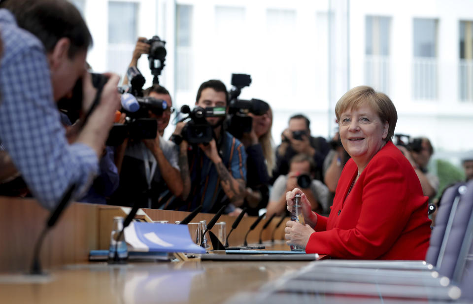German Chancellor Angela Merkel, right, smiles as she arrives for her annual sommer press conference in Berlin, Germany, Friday, July 19, 2019. (AP Photo/Michael Sohn)