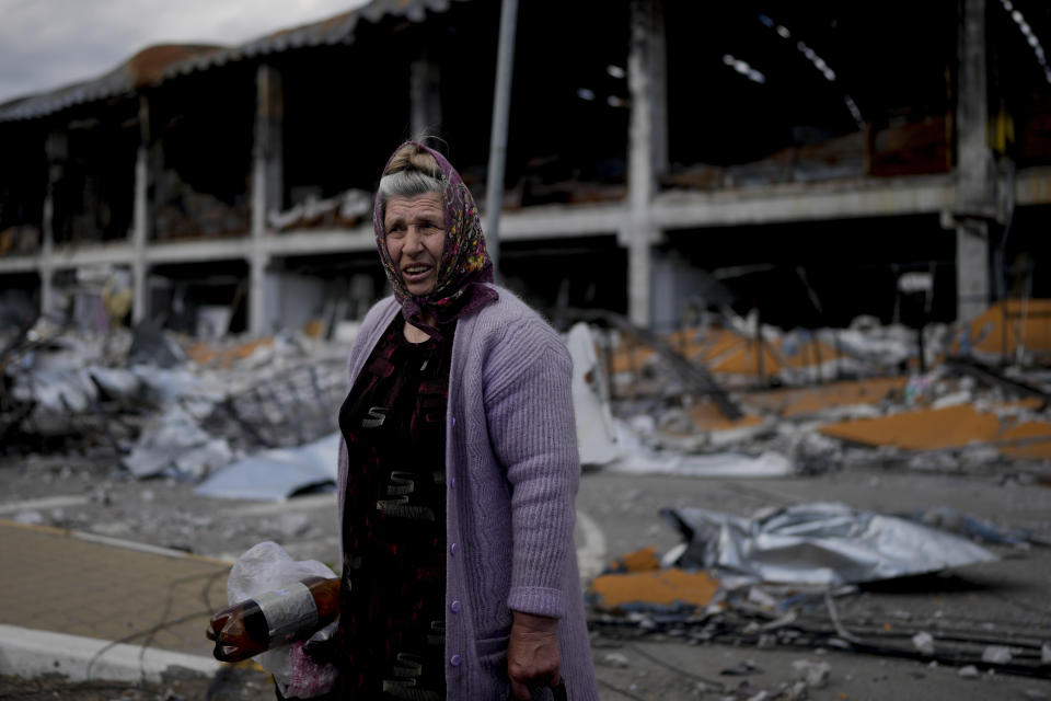 A woman stands in front of a damage building ruined by attacks in Irpin, outskirts Kyiv, Ukraine, Thursday, May 26, 2022. (AP Photo/Natacha Pisarenko)