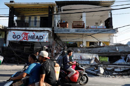 People ride motorcycles along a street next to collapsed shops after an earthquake hit on Sunday in Pemenang, Lombok island, Indonesia, August 7, 2018. REUTERS/Beawiharta