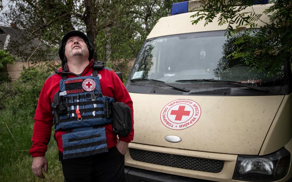 Red Cross worker Ihor Yakovlev, 46, looks for drones as he waits on the road outside the village of Rus'ki Tyshky