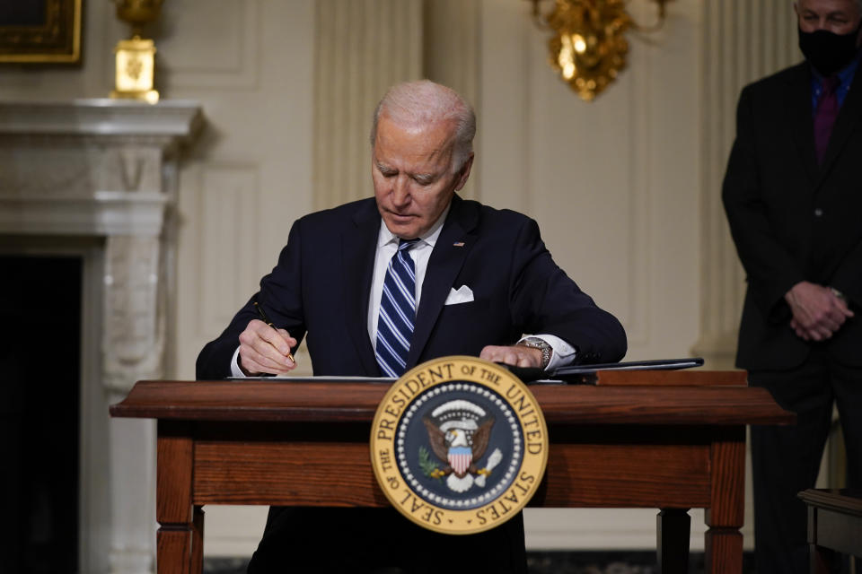 FILE - In this Jan. 27, 2021 file photo, President Joe Biden signs an executive order on climate change, in the State Dining Room of the White House in Washington. More than 300 businesses and investors are calling on the Biden administration to set an ambitious climate change goal that would cut U.S. greenhouse gas emissions by at least 50% below 2005 levels by 2030. (AP Photo/Evan Vucci)