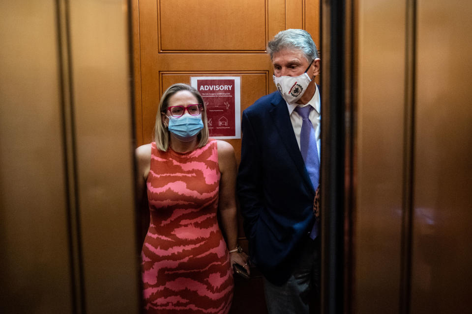 Sen. Kyrsten Sinema and Sen. Joe Manchin, both wearing masks, stand side by side in an elevator in the Senate building.