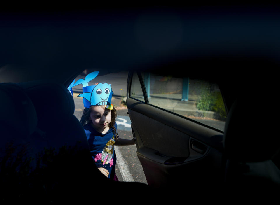 Scarlett Rasmussen, 8, gets into the car of her mother, Chelsea, after a short school day at Parkside Elementary School Wednesday, May 17, 2023, in Grants Pass, Ore. Chelsea Rasmussen has fought for more than a year for her daughter, Scarlett, to attend full days at Parkside and says school employees told her the district lacked the staff to tend to Scarlett’s medical and educational needs, which the district denies. Scarlett is nonverbal and uses an electronic device and online videos to communicate, but reads at her grade level. She was born with a genetic condition that causes her to have seizures and makes it hard for her to eat and digest food, requiring her to need a resident nurse at school. (AP Photo/Lindsey Wasson)