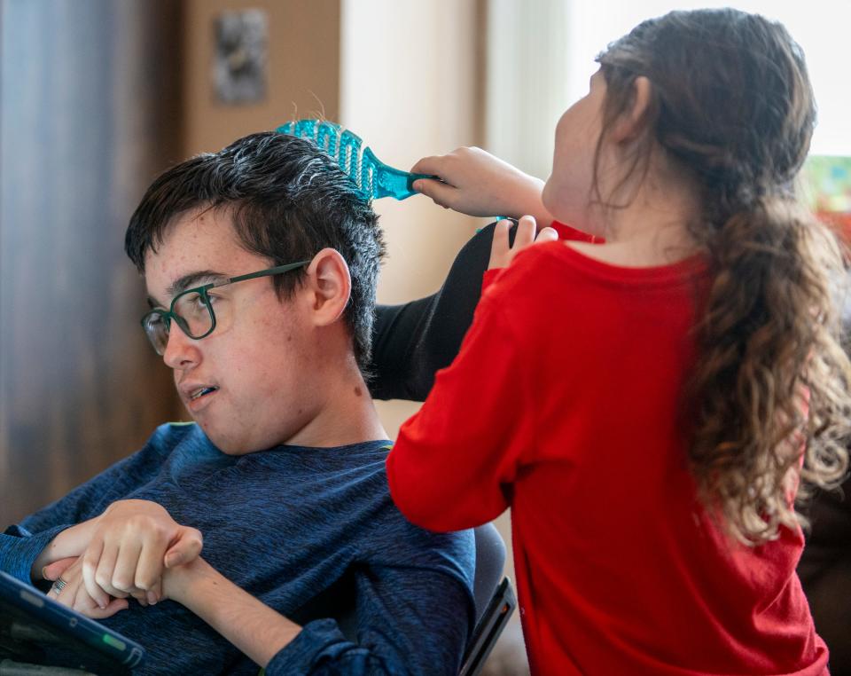 Adaline Davis, who turns eight on Jan. 25, brushes the hair of her brother Alexander Davis, 15, on Sunday, Jan 21, 2024, at the family’s Tipton home. A recent Family and Social Services Administration decision is slated to eliminate financial reimbursement for family members who care for severely disabled and medically complex children.