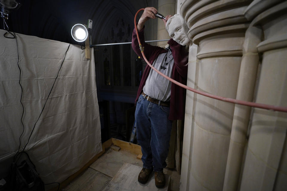 Stone carver Sean Callahan uses an air chisel during work on a sculpture of Holocaust survivor and Nobel Peace Prize winning author Elie Wiesel in the Human Rights Porch at the Washington National Cathedral, Thursday, March 25, 2021. (AP Photo/Carolyn Kaster)