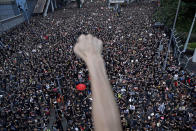 FILE - A protester raises a fist near protesters marching on the streets against an extradition bill in Hong Kong on June 16, 2019. From the military suppression of Beijing’s 1989 pro-democracy protests to the less deadly crushing of Hong Kong’s opposition four decades later, China’s long-ruling Communist Party has demonstrated a determination and ability to stay in power that is seemingly impervious to Western criticism and sanctions. (AP Photo/Vincent Yu, File)