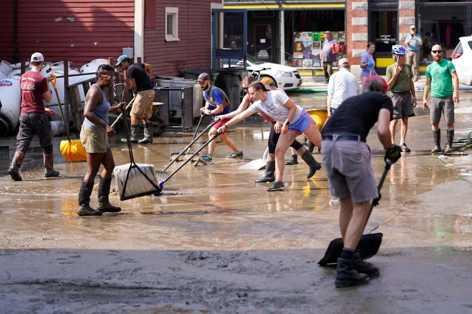 Volunteers clean up a downtown parking area on the banks of the Winooski River, Wednesday, July 12, 2023, in Montpelier, Vt. Following a storm that dumped nearly two months of rain in two days, Vermonters are cleaning up from the deluge of water.