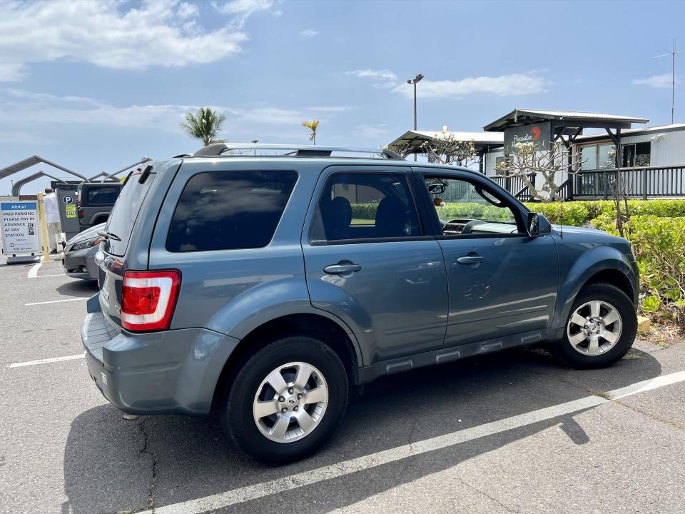 A blue ford escape parked in parking lot outside