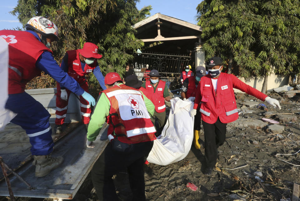 Indonesian red cross team carry the body of a tsunami victim following a massive earthquake and tsunami at Talise beach in Palu, Central Sulawesi, Indonesia, Monday, Oct. 1, 2018. Bright-colored body bags were placed side-by-side in a freshly dug mass grave Monday, as a hard-hit Indonesian city began burying its dead from the devastating earthquake and tsunami. (AP Photo/Tatan Syuflana)