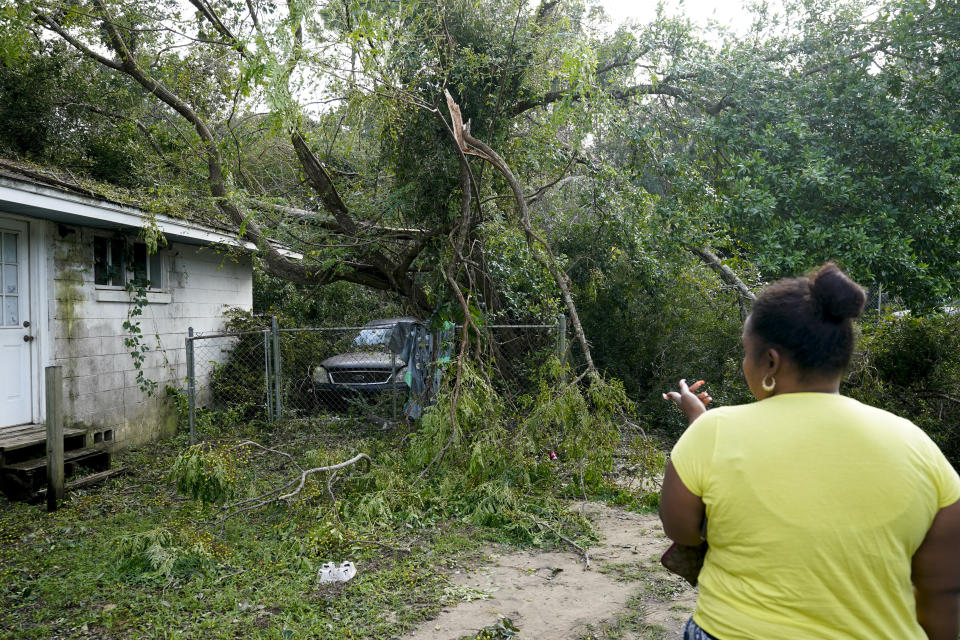 Seleka Souls looks over a neighbor's home that was damaged by Hurricane Sally, Friday, Sept. 18, 2020, in Pensacola, Fla. (AP Photo/Gerald Herbert)