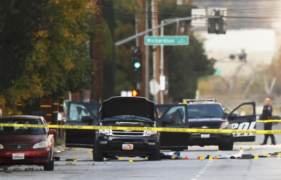 A police investigator is seen around a vehicle (C) in which two suspects were shot following a mass shooting in San Bernardino, California December 3, 2015. Authorities on Thursday were working to determine why Syed Rizwan Farook, 28, and Tashfeen Malik, 27, who had a 6-month-old daughter together, opened fire at a holiday party of his co-workers in Southern California, killing 14 people and wounding 17 in an attack that appeared to have been planned. REUTERS/Mike Blake