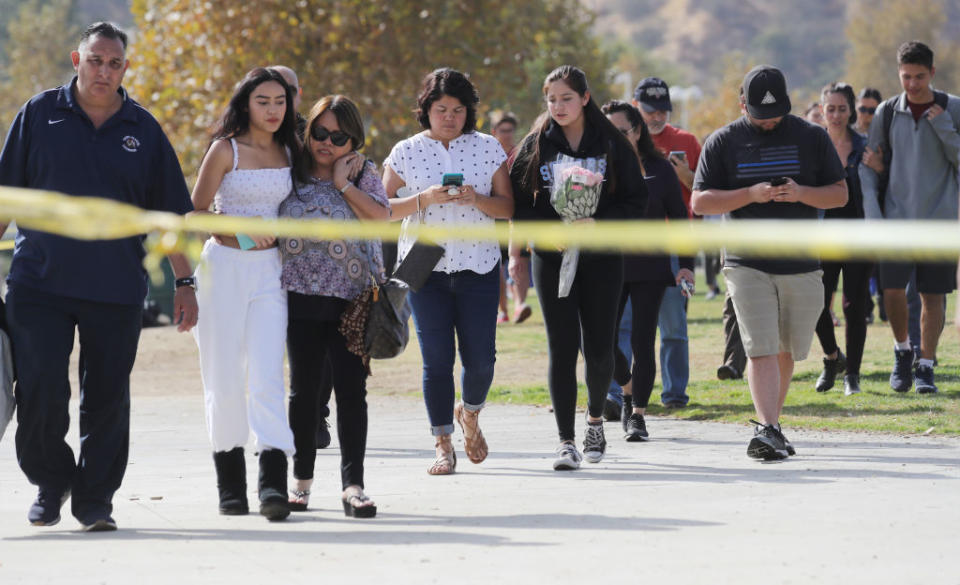 Students and family members walk after being reunited at a park near Saugus High School after the shooting. Source: Getty