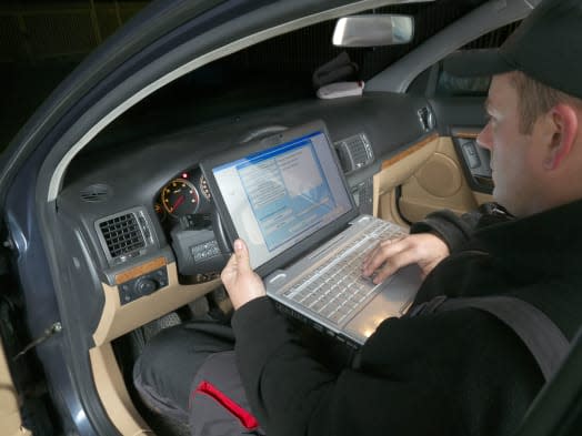 Auto mechanic checking vehicle identification number of the car using laptop hooked up to the car onboard computer