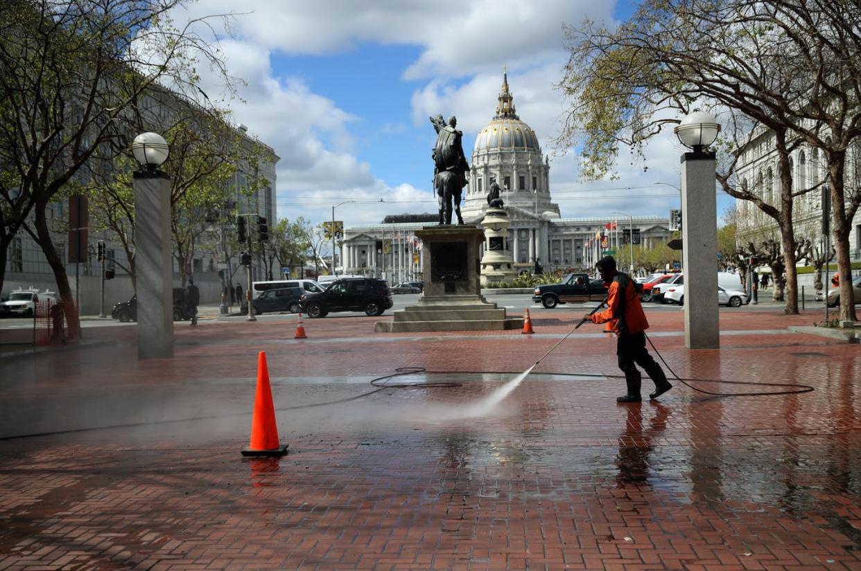 <span class="caption">A worker washes the sidewalk near San Francisco's City Hall.</span> <span class="attribution"><a class="link " href="https://www.gettyimages.com/detail/news-photo/worker-power-washes-the-sidewalk-near-san-francisco-city-news-photo/1212815590?adppopup=true" rel="nofollow noopener" target="_blank" data-ylk="slk:Justin Sullivan/Getty Images;elm:context_link;itc:0;sec:content-canvas">Justin Sullivan/Getty Images</a></span>