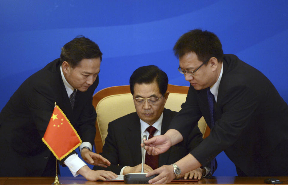 Chinese President Hu Jintao, center, gets a helping hand from his aides as he prepares to deliver his speech after a signing ceremony at the Shanghai Cooperation Organization (SCO) summit in the Great Hall of the People in Beijing, China Thursday, June 7, 2012. (AP Photo/Mark Ralston, Pool)