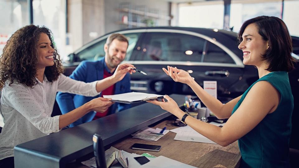 Couple is buying new car and signing the contract.