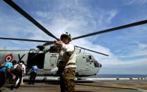 A U.S. Marines Corps personnel guides the media on board the USS Boxer LHD as a helicopter prepares for takeoff at a location off Goa in this October 29, 2006 file photo. REUTERS/Prashanth Vishwanathan/Files