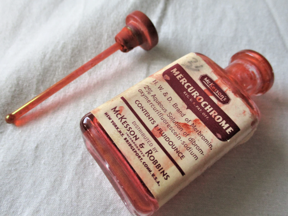 A vintage bottle of Mercurochrome antiseptic with a glass dropper detached. The label shows 2% aqueous solution and manufacturer details: McKesson & Robbins