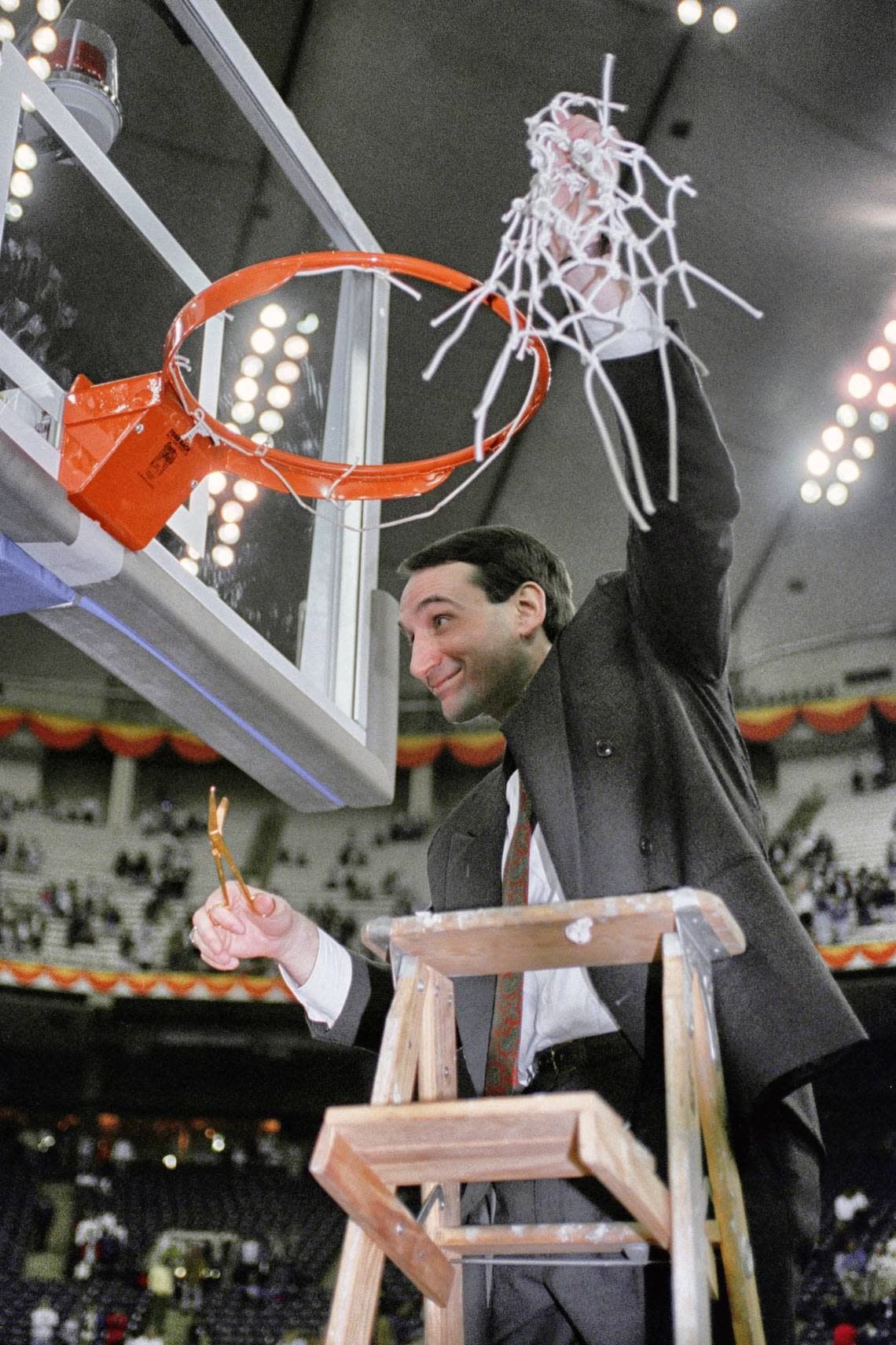 In this April 2, 1991, file photo, Duke coach Mike Krzyzewski finishes the traditional net cutting in the Indianapolis Hoosier Dome after Duke defeated Kansas 72-65 in the NCAA Final Four championship game. Recouping from a 30-point loss in the previous year’s NCAA championship game, Duke beat top-ranked UNLV and then Kansas to win the championship for the first time.