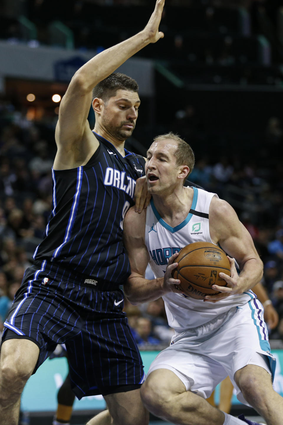 Charlotte Hornets forward Cody Zeller, right, drives into Orlando Magic center Nikola Vucevic in the first half of an NBA basketball game in Charlotte, N.C., Monday, Jan. 20, 2020. (AP Photo/Nell Redmond)