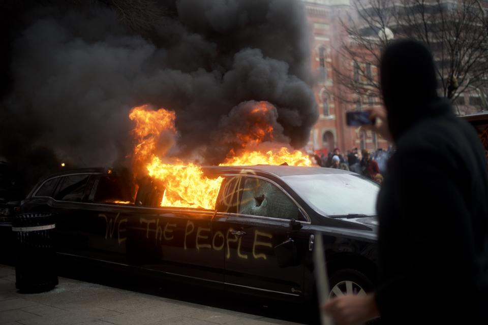 A limousine with the graffiti of "We the People" spray-painted on the side is set ablaze. (Photo: Mark Makela/Getty Images)