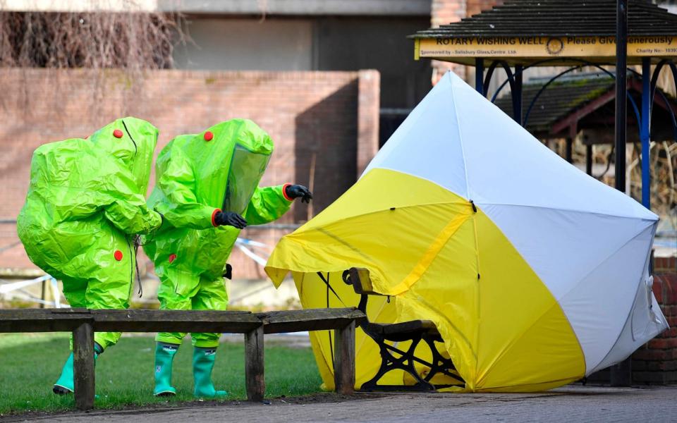 Emergency responders in biohazard suits at the bench in Salisbury where Sergei Skripal and his daughter Yulia were found poisoned in March - AFP