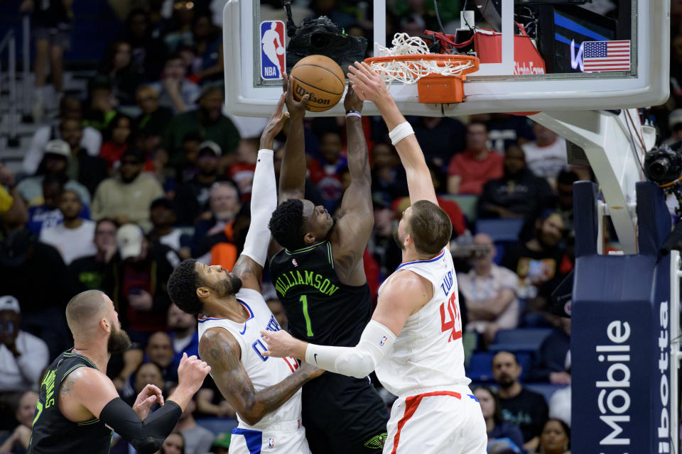 New Orleans Pelicans forward Zion Williamson (1) shoots between Los Angeles Clippers forward Paul George, second from left, and center Ivica Zubac (40) during the first half of an NBA basketball game in New Orleans, Friday, March 15, 2024. (AP Photo/Matthew Hinton)