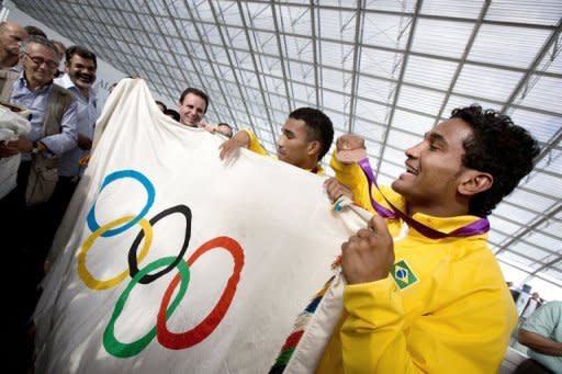 Image provided by Air France on August 13 shows Brazilian boxers, bronze medalist Yamaguchi Falcao Florentino (R) and silver medalist Esquiva Falcao Florentino (2nd R), holding the Olympic flag with Rio de Janeiro Mayor Eduardo Paes (3rd R) prior to boarding a flight to Rio de Janeiro at Charles De Gaulle airport in Roissy, France