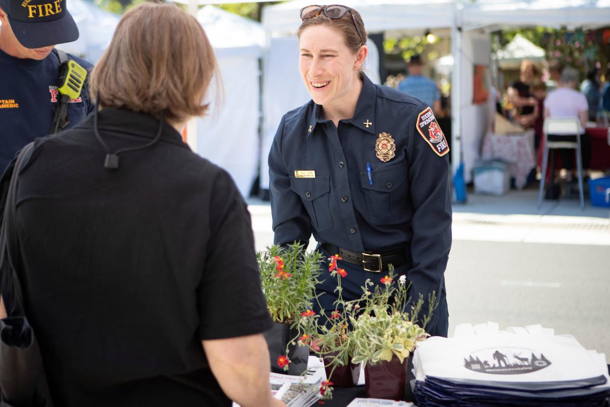 Deputy Fire Marshal Althea Sullivan talks with community members while staffing a booth at the Eugene Saturday Market to raise awareness about wildfire preparedness during Wildfire Preparedness Month Saturday, May 11, 2024, in Eugene.