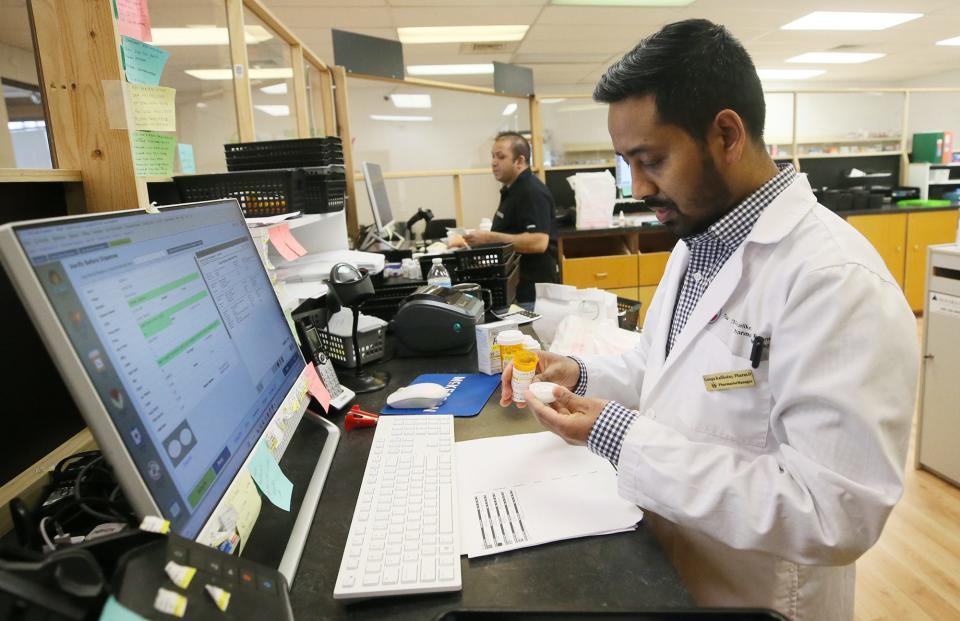 Ganga Kalikotay, pharmacist at BestCare Pharmacy, verifies a prescription before sending it out at his pharmacy in Akron on Monday.