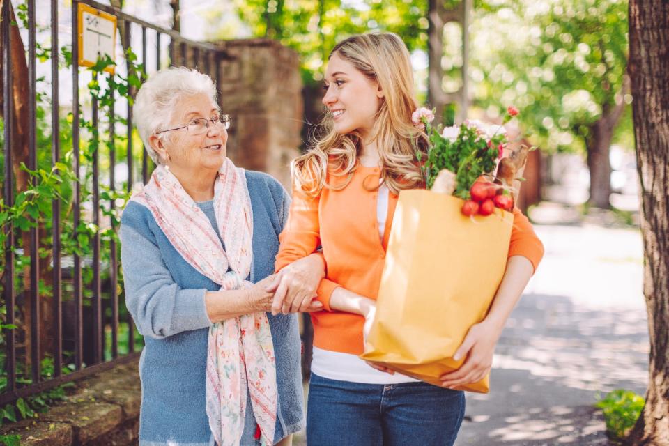 A teenager helps a grandmother with groceries.