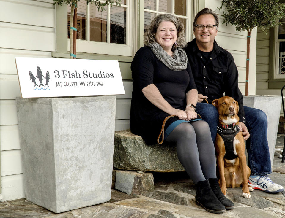 Husband and wife artist team Annie Galvin, left, and Eric Rewitzer pose with their dog Woody in front of their new 3 Fish Studios art gallery in Amador City, Calif., in 2023. Galvin and Rewitzer moved out of San Francisco to live closer to nature after their sabbatical in France and Ireland. (Eric Rewitzer via AP)