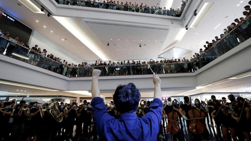 香港九龍塘又一城購物商場內一位「反送中」示威者充當指揮帶領其他示威者合唱《願榮光歸香港》（18/9/2019）