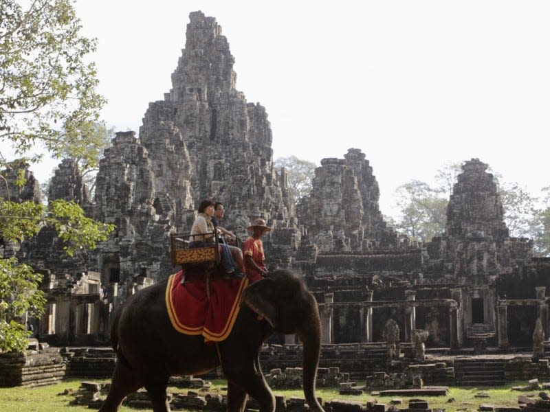 Tourists ride an elephant past the ruins of Cambodia's Bayon temple in Siem Reap December 22, 2012. Picture taken December 22, 2012.  REUTERS/Erik De Castro