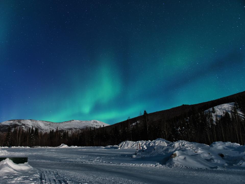 A view of the green northern lights over mountain peaks in Alaska