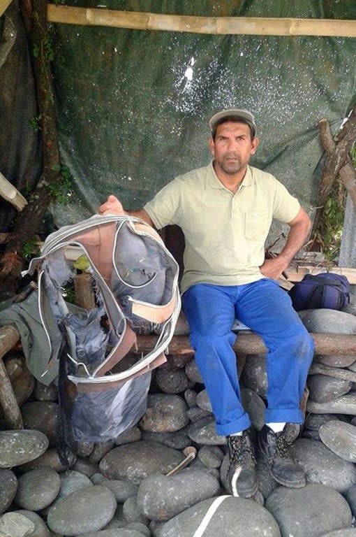 Johnny Begue, a member of a local shore cleaning association, poses on July 30, 2015 in Saint-Andre, on the French island of La Reunion, with the remains of a suitcase