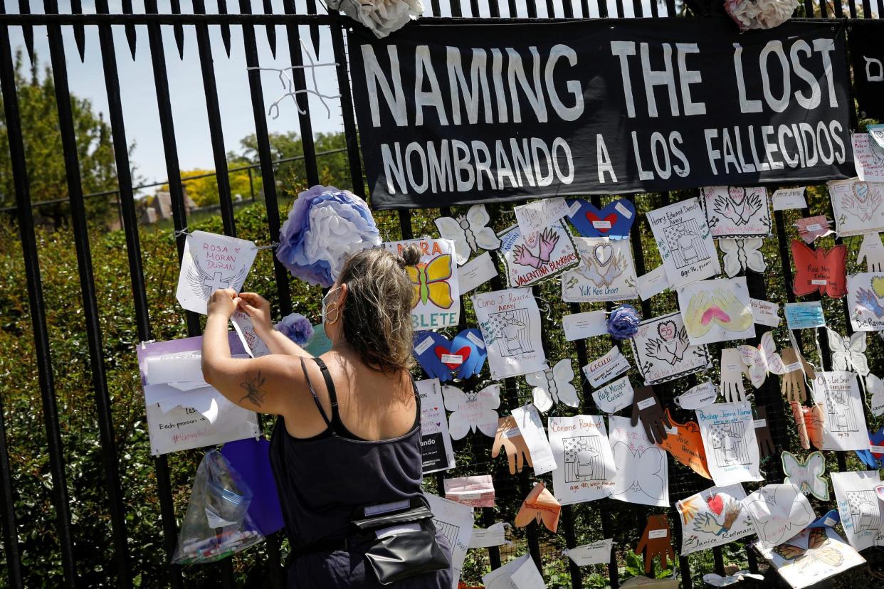 A woman adds a name to a memorial for those who have died from the coronavirus, outside a cemetery in Brooklyn, New York: REUTERS