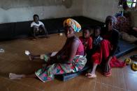 Diana Essandoh, 25, whose husband died in an explosion when carrying mining explosives detonated along a road in Apiate, sits with her children and mother-in-law, at a shelter for displaced victims in Bogoso